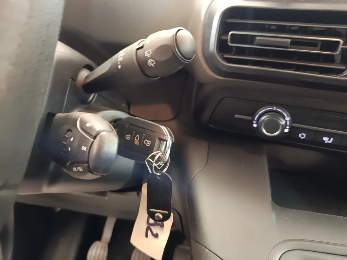 Gros plan sur la clé insérée dans le contacteur, avec commandes au volant et tableau de bord noir du Peugeot Rifter.