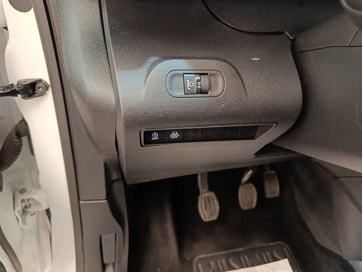 Gros plan sur les commandes d’éclairage et d’assistance côté gauche du Peugeot Rifter blanc, avec pédales manuelles visibles.