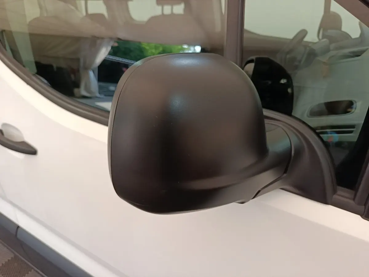 Gros plan sur le rétroviseur côté conducteur noir d’un Peugeot Rifter blanc, vue latérale gauche.