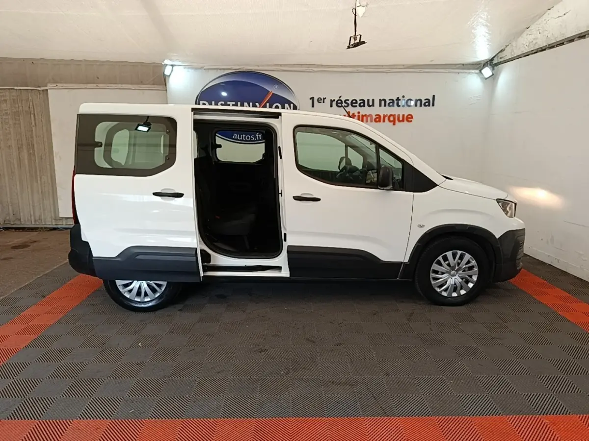 Peugeot Rifter blanc vue de profil droit avec porte coulissante arrière ouverte dans un garage.