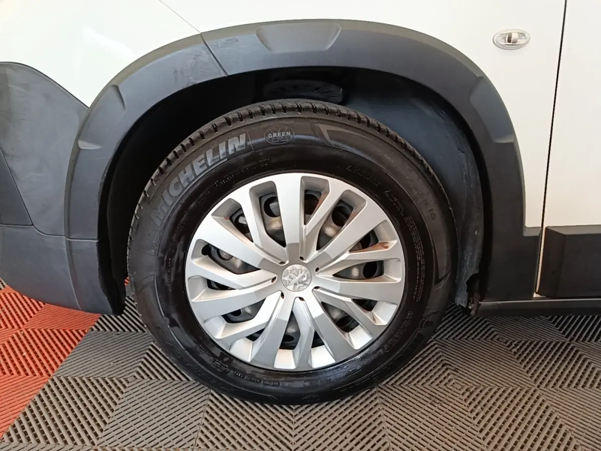 Gros plan sur la roue avant droite d’un Peugeot Rifter blanc, avec jante argentée et pneu Michelin.