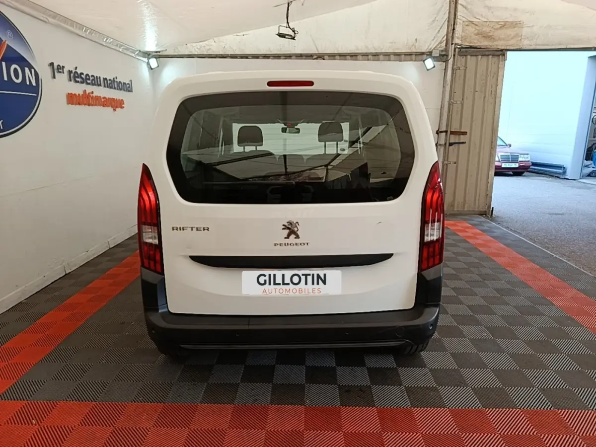 Vue arrière d'un Peugeot Rifter blanc 2020 garé en intérieur avec feux arrière verticaux rouges visibles.