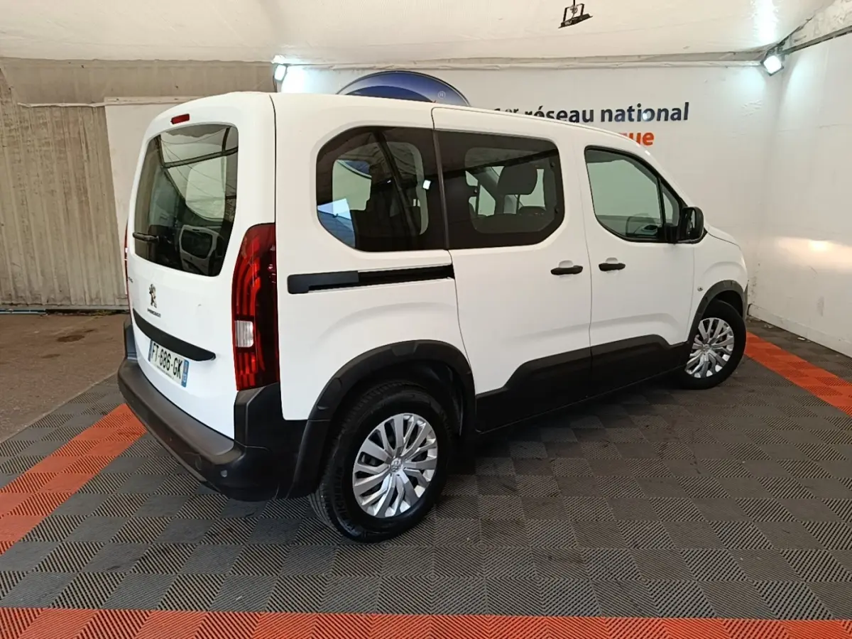 Vue 3/4 arrière droite d’un Peugeot Rifter blanc 2020 avec vitres teintées et protections noires sur les bas de caisse.