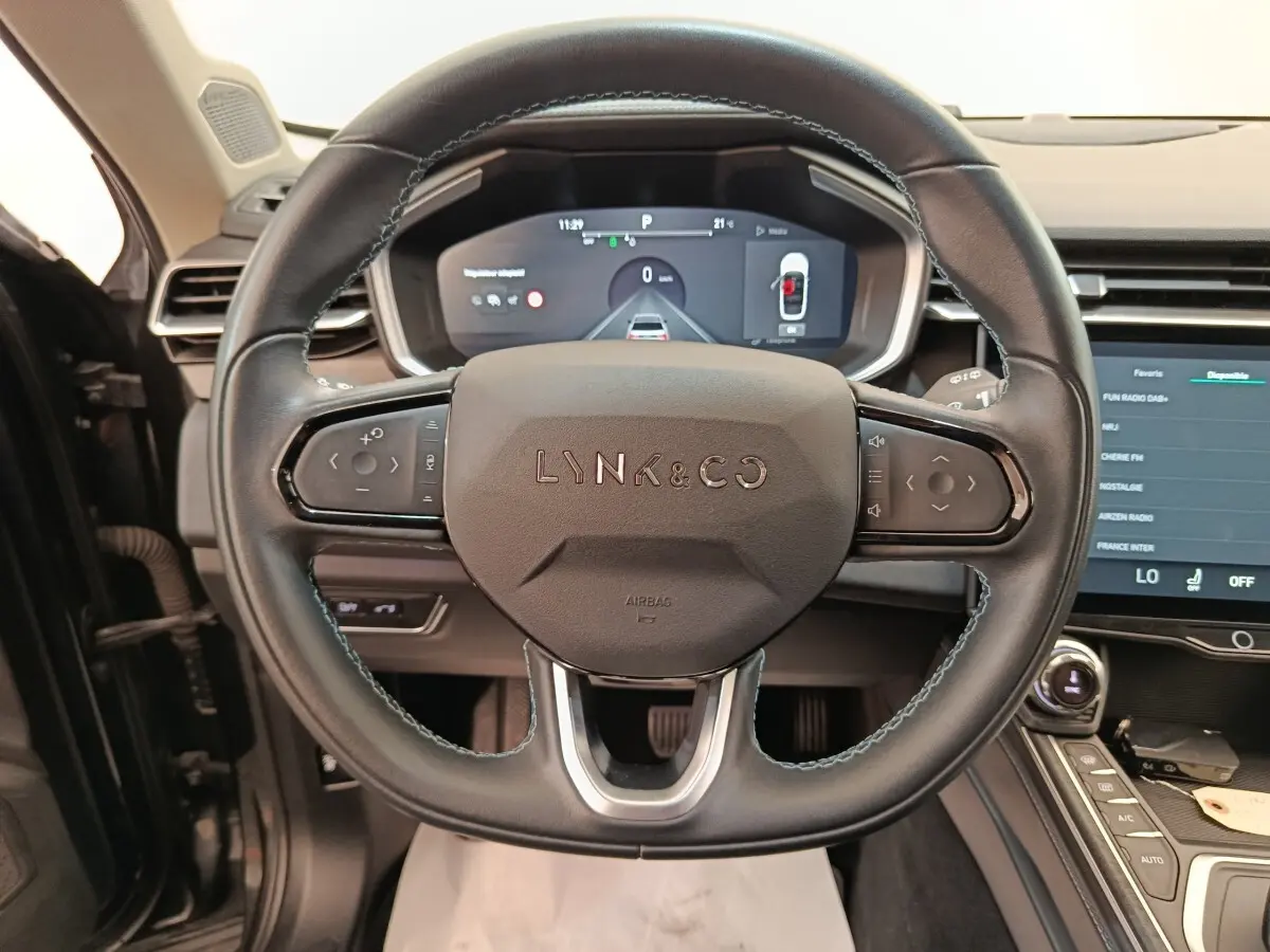 Vue intérieure centrée sur le volant cuir noir du Lynk & Co 01 avec tableau de bord digital et écran tactile.