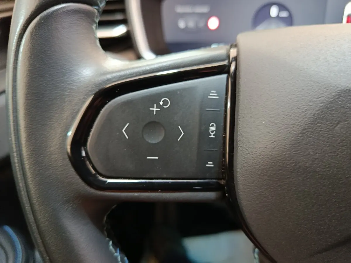 Gros plan sur les commandes noires du volant côté gauche du LINK & CO 01 hybride rechargeable 2022.