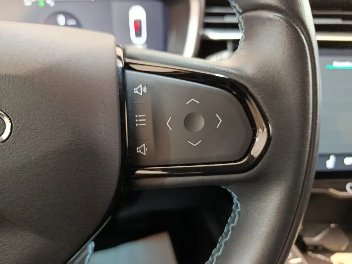 Gros plan sur les commandes tactiles noires du volant en cuir noir avec surpiqûres bleues du LINK & CO 01 hybride rechargeable.