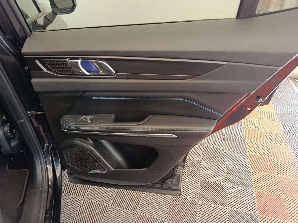 Vue intérieure côté gauche de la porte avant d’un Link & Co 01 bleu, avec éclairage d’ambiance bleu et finitions noires.