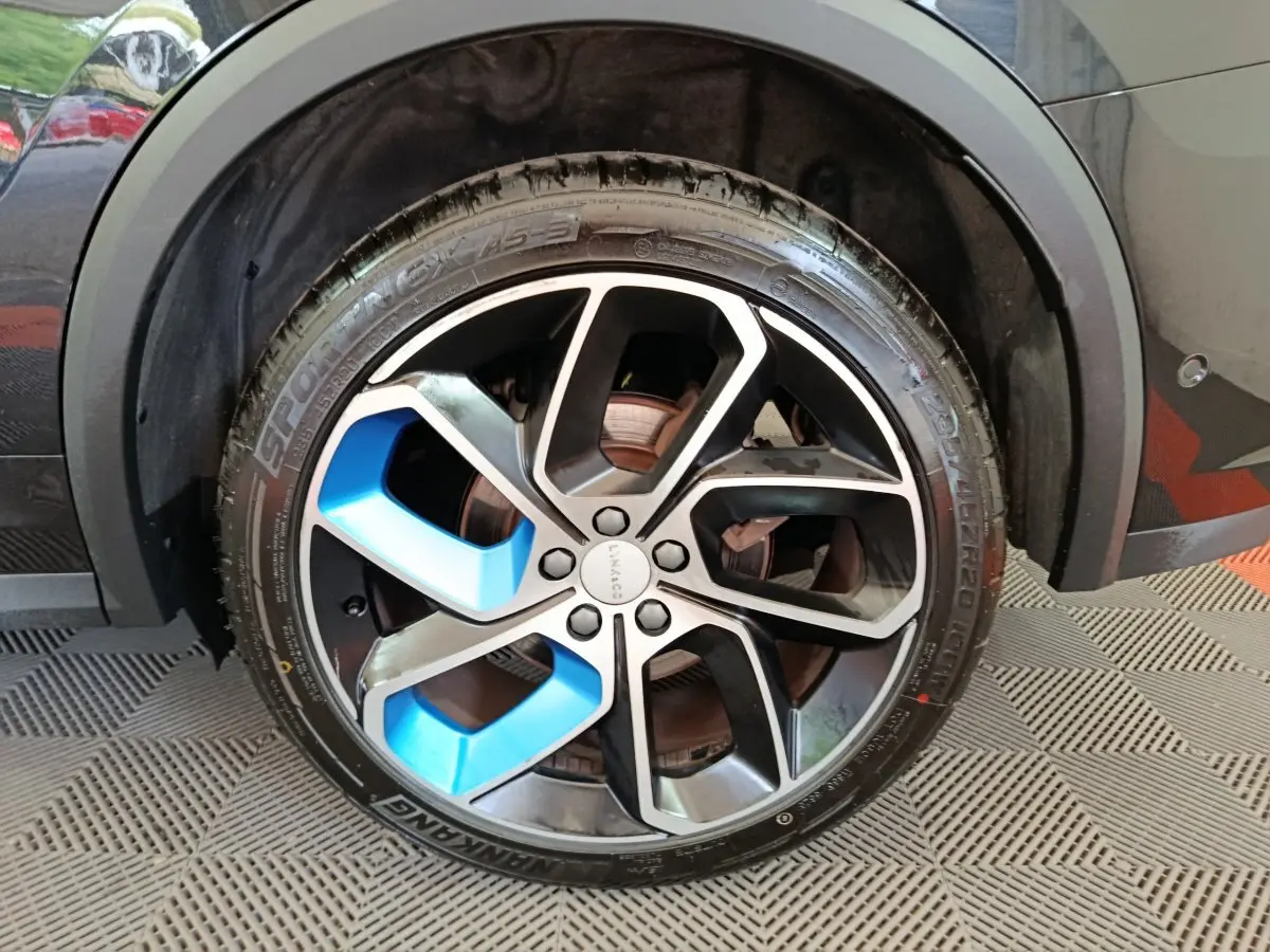 Gros plan sur la roue avant droite du SUV Link & Co 01 bleu, avec jante noire et inserts bleus distinctifs.