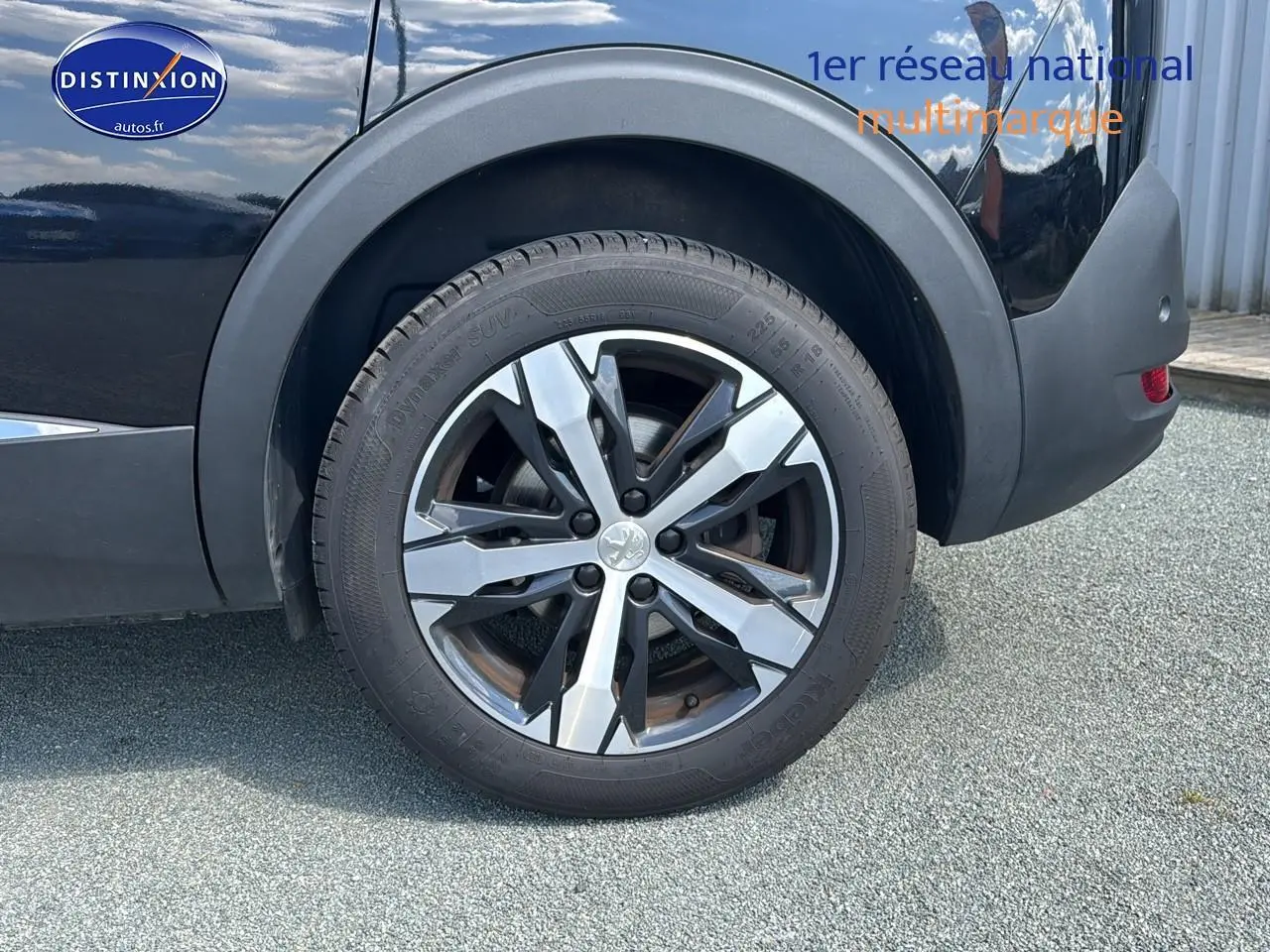 Gros plan sur la roue arrière droite du Peugeot 5008 noir métal, mettant en valeur la jante alu au design moderne.