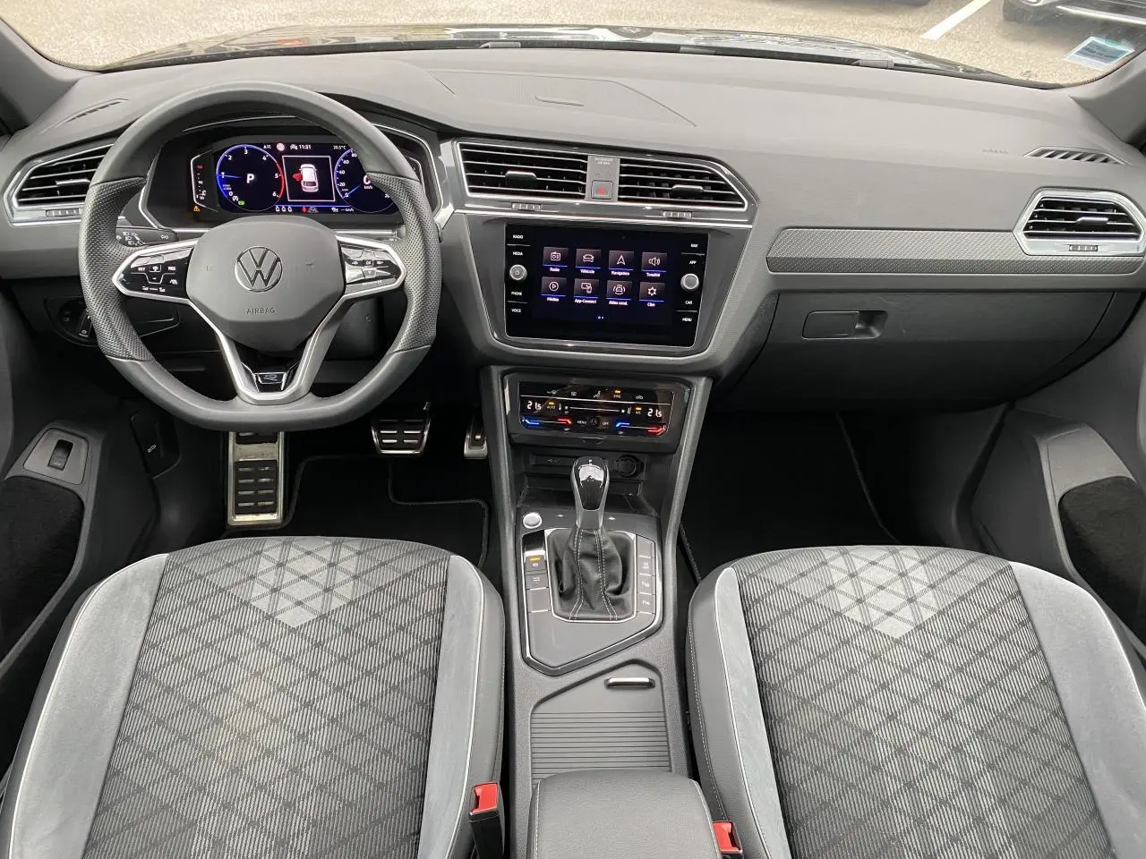 Intérieur du Volkswagen Tiguan 2023 vu de face, avec tableau de bord numérique et sellerie tissu gris à motifs géométriques.