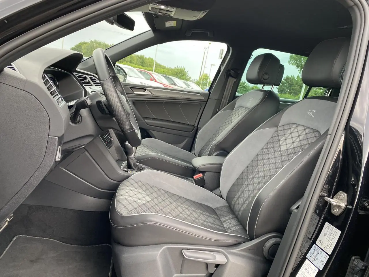 Intérieur avant du Volkswagen Tiguan 2023 noir intense, sièges sport en tissu et microfleece gris avec surpiqûres R-Line.