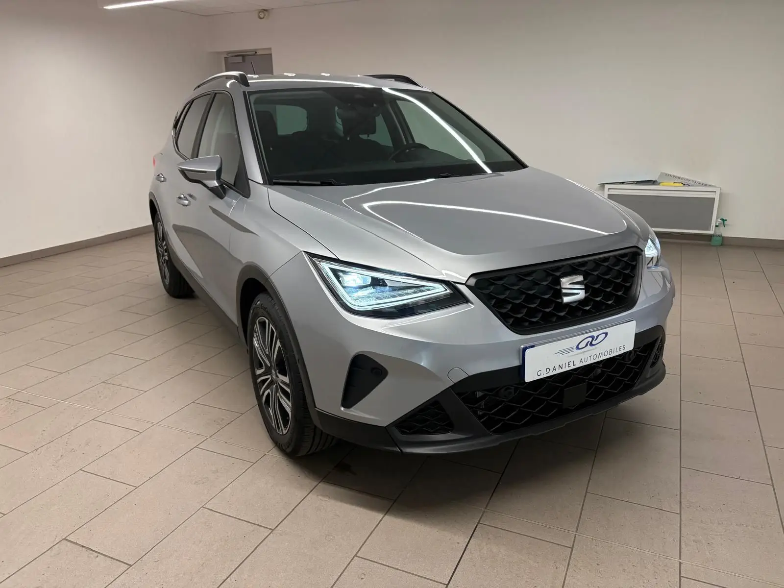 SEAT Arona 2024 gris urbain en 3/4 avant droit avec vitres arrière surteintées et calandre noire.