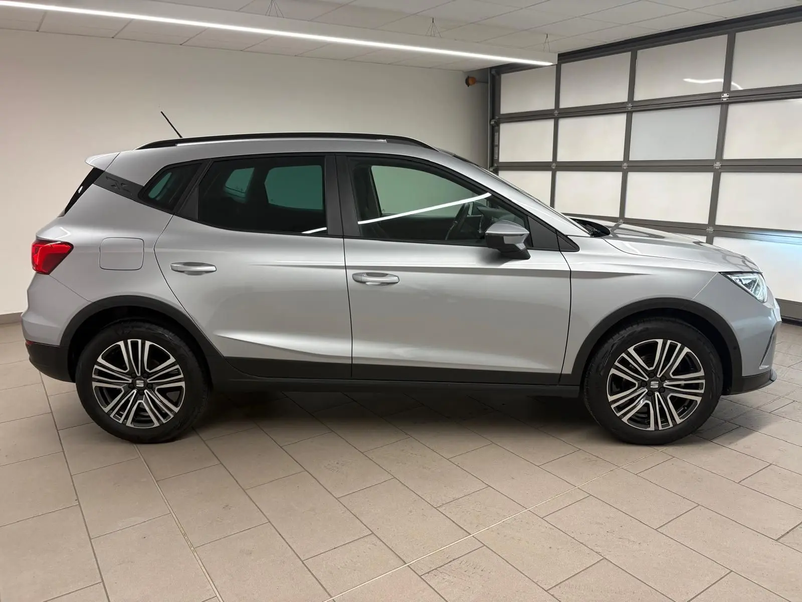 Profil droit d'un SEAT Arona 2024 gris urbain avec vitres arrière surteintées et jantes alliage en intérieur neutre.