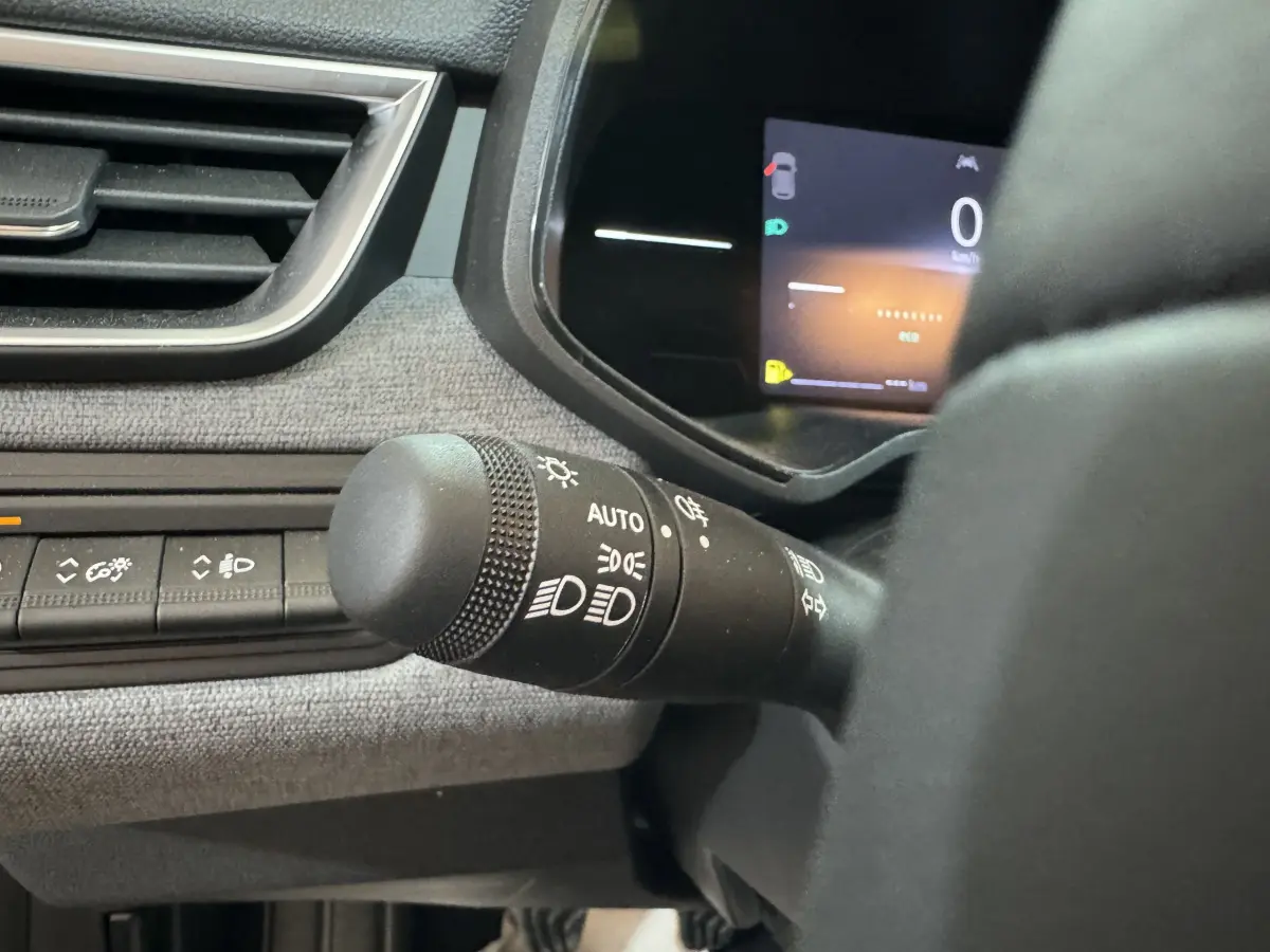 Gros plan sur la commande des phares et tableau de bord numérique de la Renault Clio gris clair, version Evolution Blue dCi 100 -25.