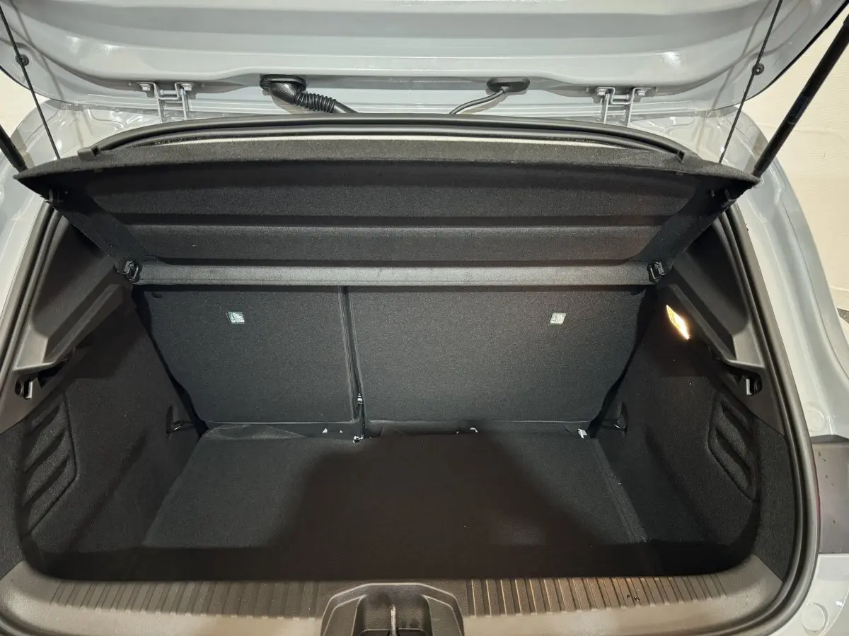 Coffre ouvert vu de l'arrière d'une Renault Clio gris clair 2025, montrant l'espace de chargement vide et la tablette amovible.
