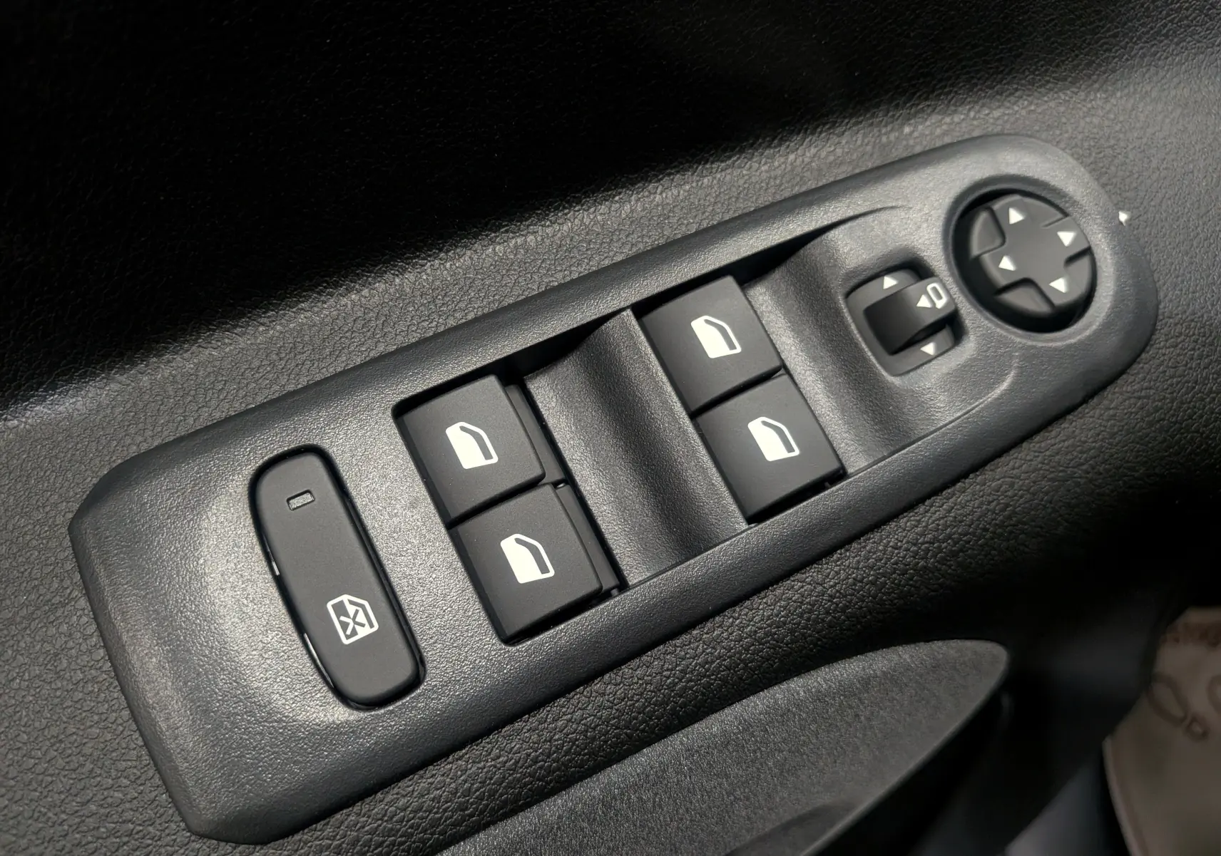 Gros plan sur les commandes de lève-vitres et réglage des rétroviseurs côté conducteur d’un Peugeot Rifter gris acier 2025.