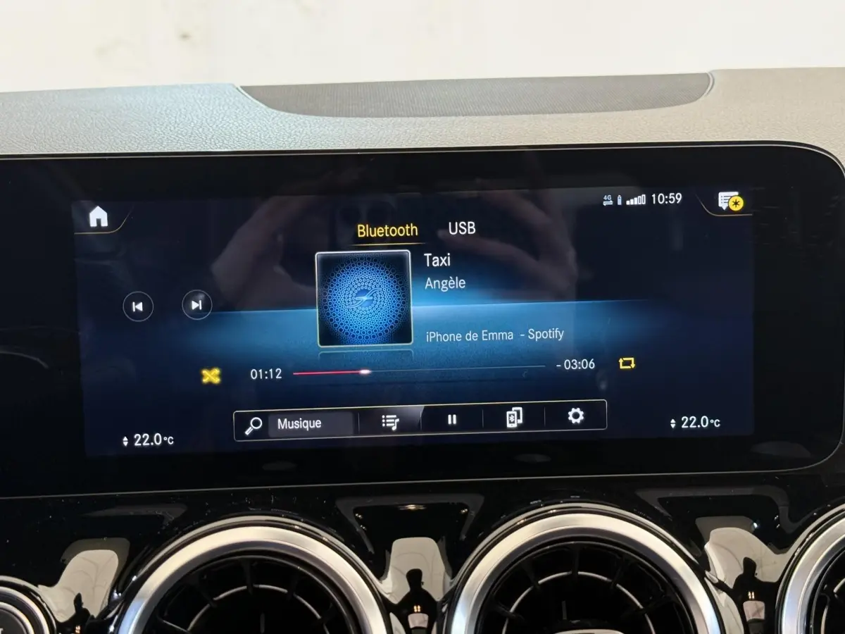 Écran tactile central de la Mercedes GLA 250 e AMG Line gris clair, affichant la musique via Bluetooth.