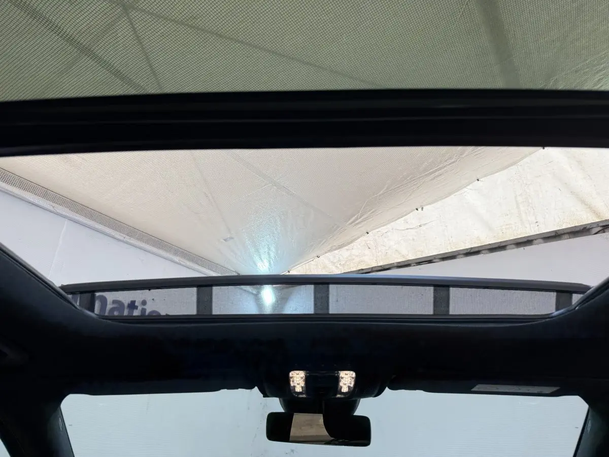 Vue intérieure du toit ouvrant panoramique du Mercedes GLA 250 e AMG Line gris clair, avec éclairage intérieur allumé.