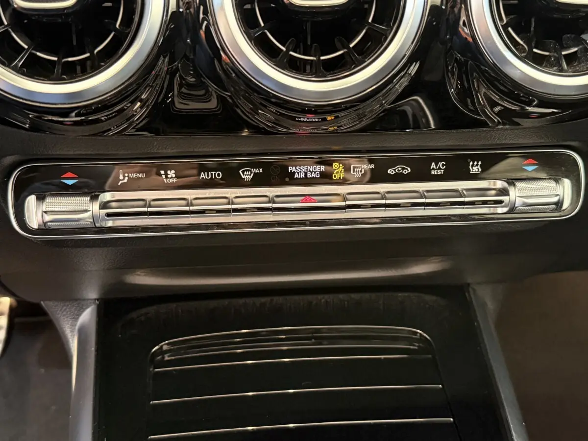 Détail du tableau de bord noir avec commandes climatisation et aérateurs ronds chromés d'une Mercedes GLA 250 e AMG Line 2023.