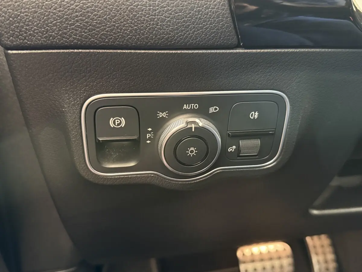 Détail du panneau de commande des phares et frein à main électrique sur tableau de bord noir du Mercedes GLA 250 e AMG Line.