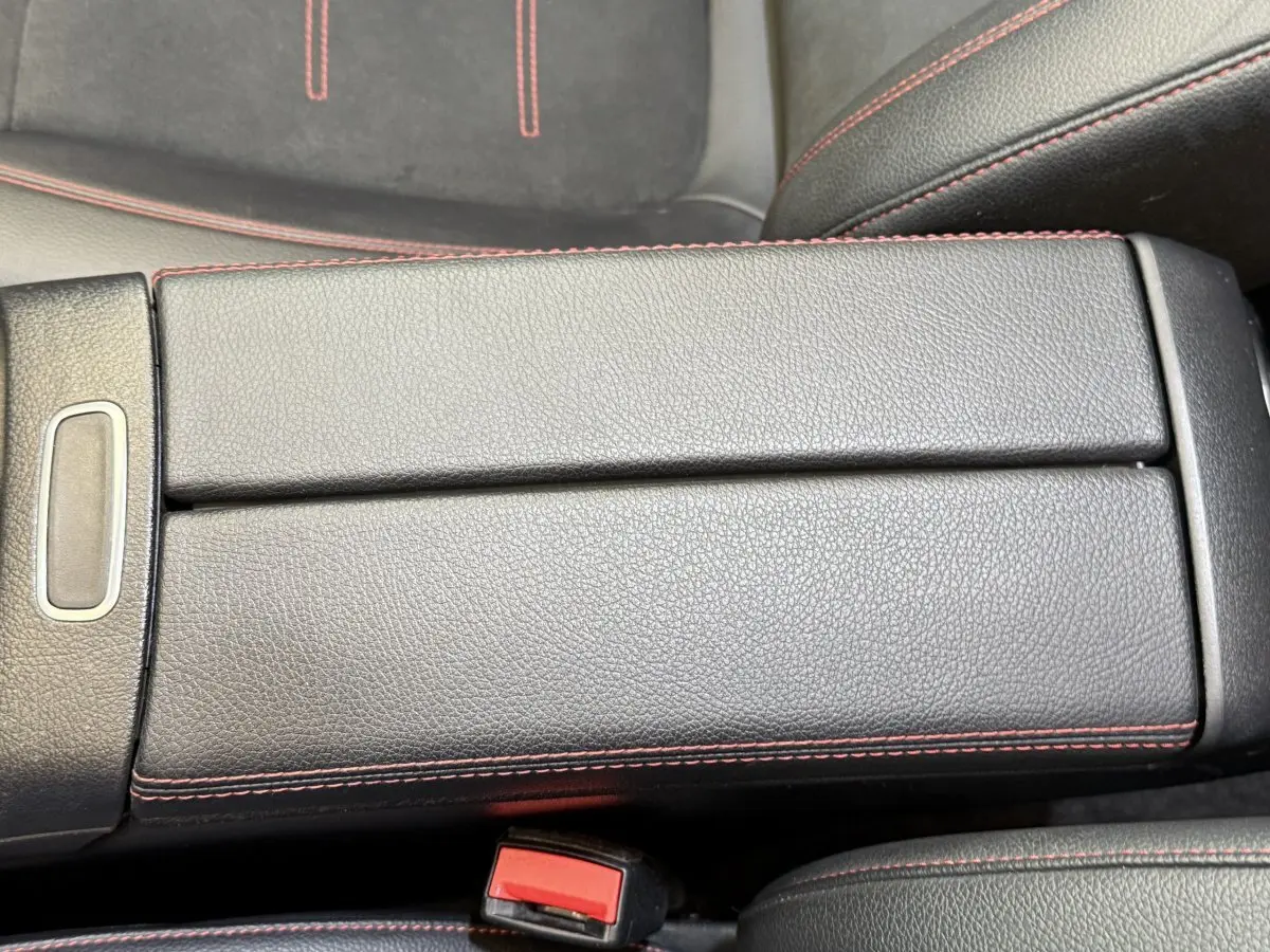 Gros plan sur l'accoudoir central en cuir noir avec surpiqûres rouges dans une Mercedes GLA 250 e AMG Line 2023.