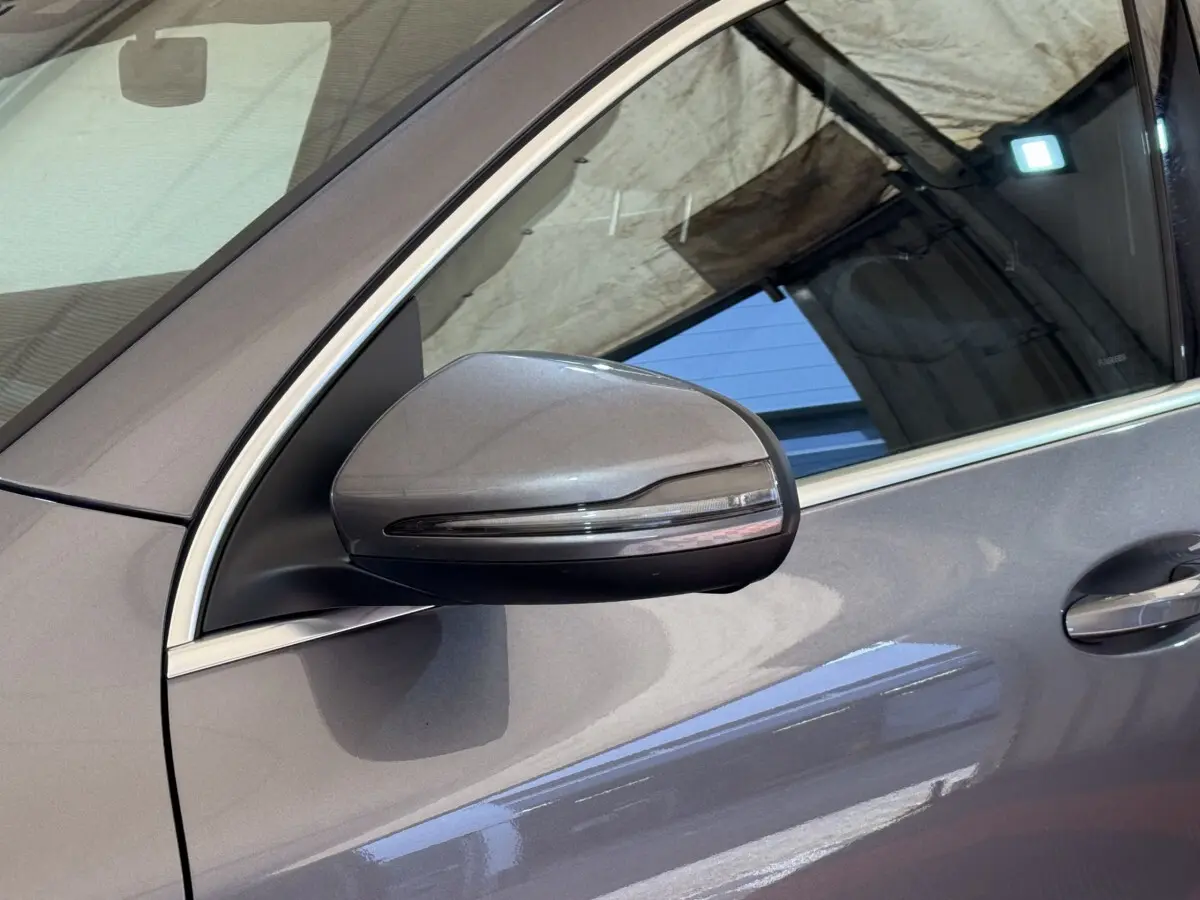 Gros plan sur le rétroviseur côté gauche gris clair du Mercedes GLA 250 e AMG Line 2023 avec cadre de fenêtre chromé.