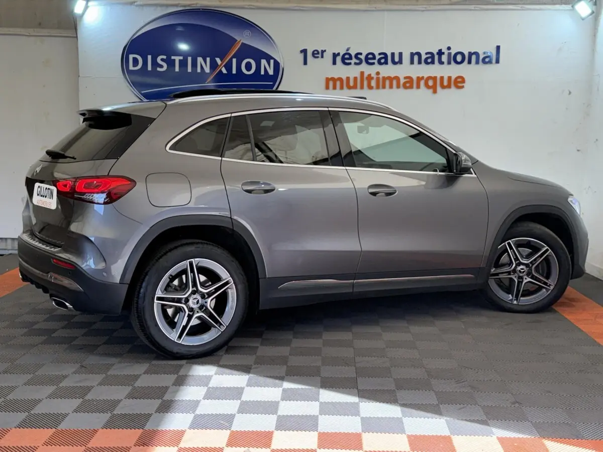 Vue de profil côté droit d’un Mercedes GLA 250 e AMG Line gris clair dans un showroom avec logo Distinxion en arrière-plan.