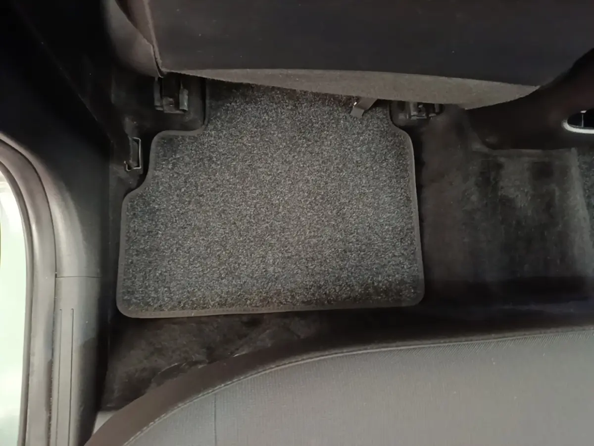 Vue rapprochée du tapis de sol gris foncé côté passager arrière d'un Hyundai Kona vert 2024.