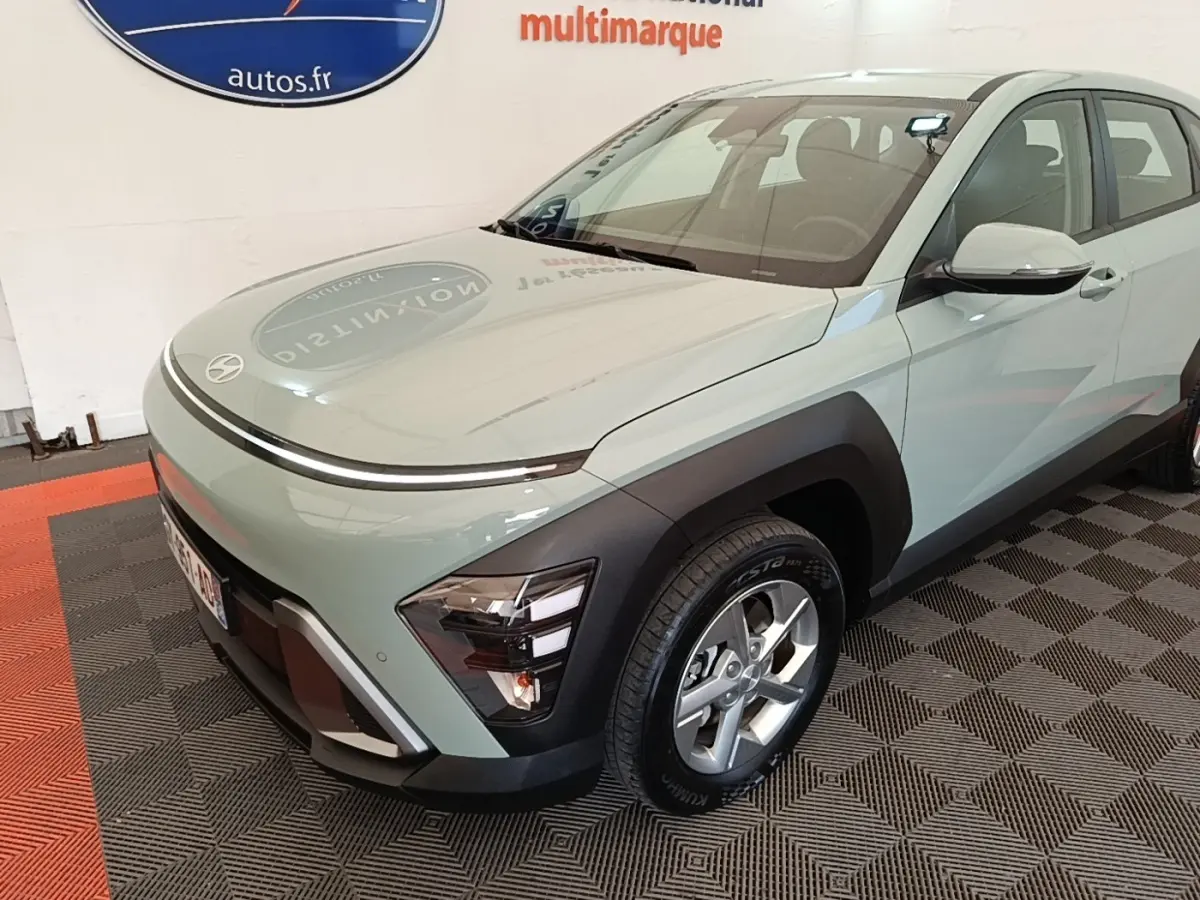 Vue 3/4 avant droite d'une Hyundai Kona 2024 vert clair avec phares LED et protections noires sur les ailes.