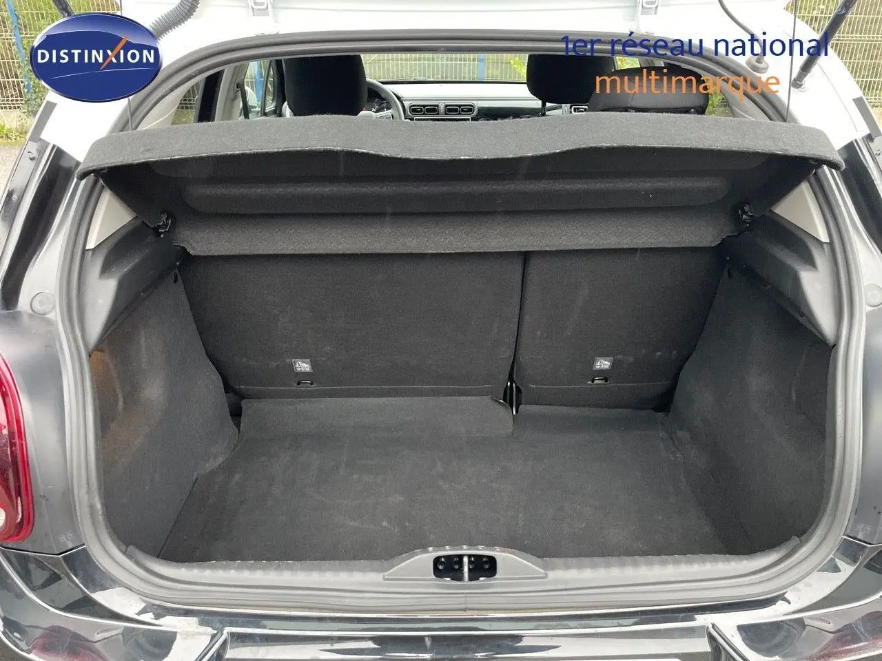 Coffre ouvert vu de l'arrière d'une Citroën C3 noire métal 2023, montrant l'espace de chargement vide.