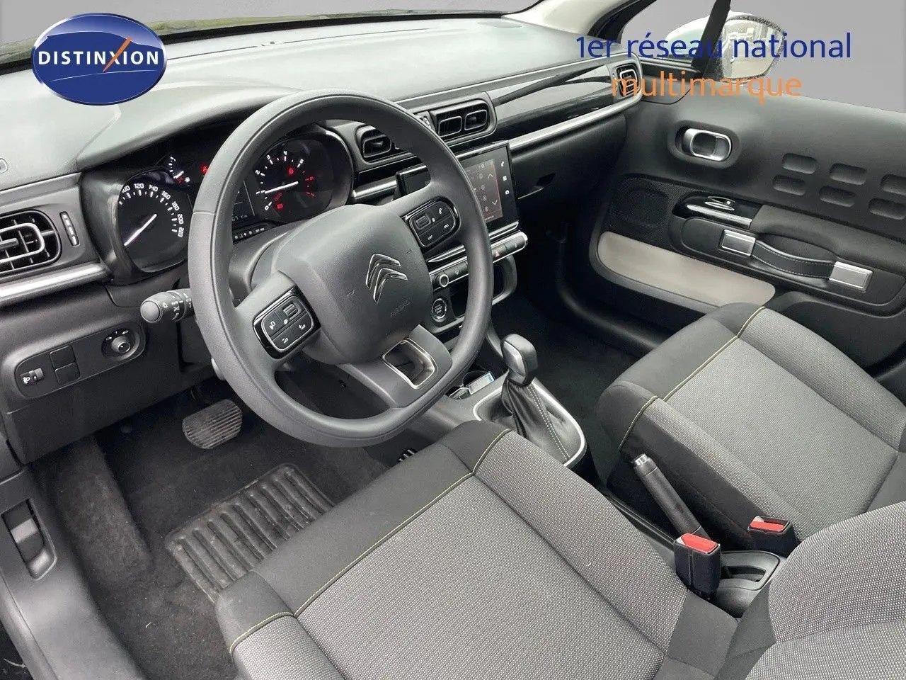 Intérieur de la Citroën C3 2023 en tissu gris, vue côté conducteur montrant tableau de bord et volant multifonction.