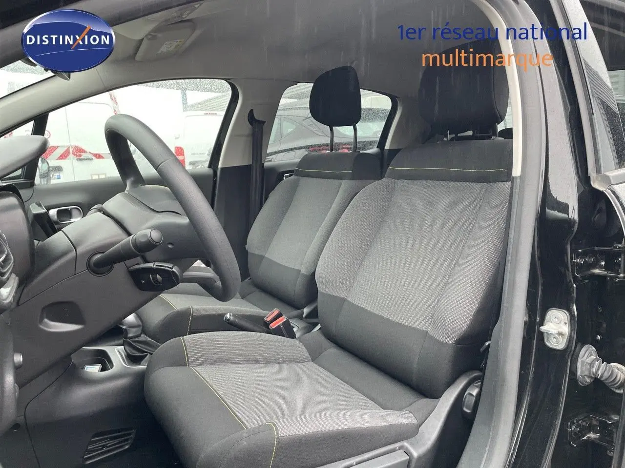Vue intérieure côté conducteur de la Citroën C3 2023 noire métal, sièges tissu gris et noir avec surpiqûres jaunes.