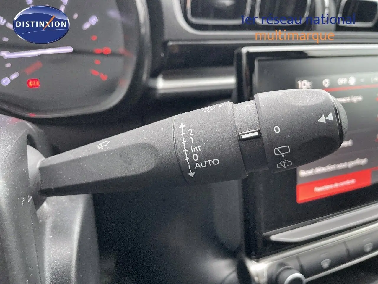 Gros plan sur la commande d'essuie-glace à gauche du volant dans l'habitacle d'une Citroën C3 noire 2023.