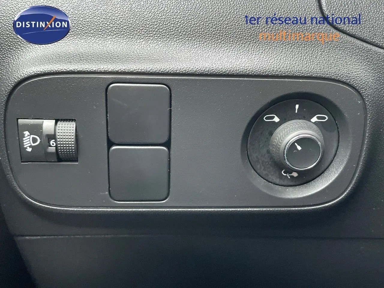 Commande de réglage des phares et des rétroviseurs sur le tableau de bord intérieur d'une Citroën C3 noire métallisée 2023.