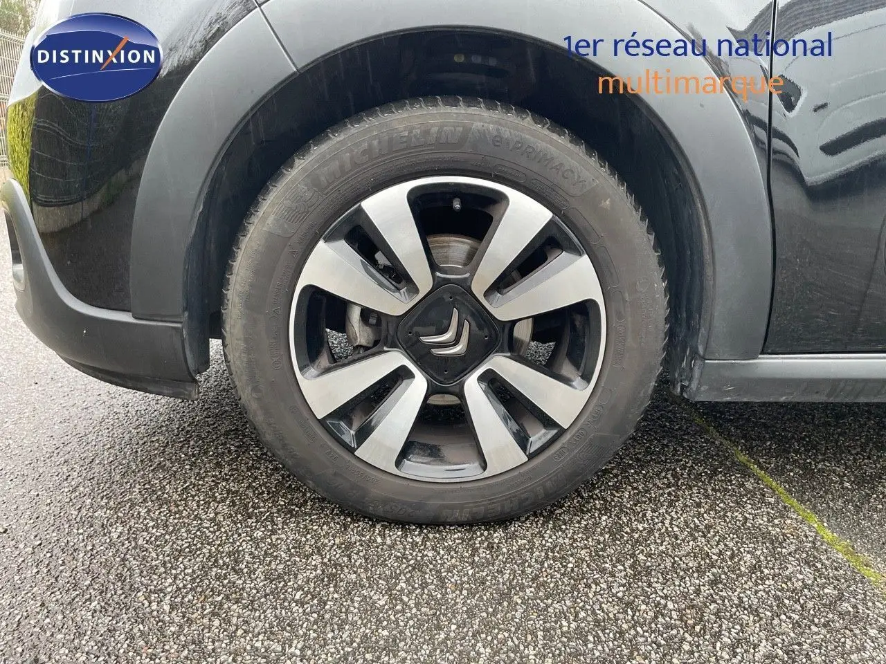 Gros plan sur la roue avant gauche d'une Citroën C3 noire métal avec jante alliage bicolore.