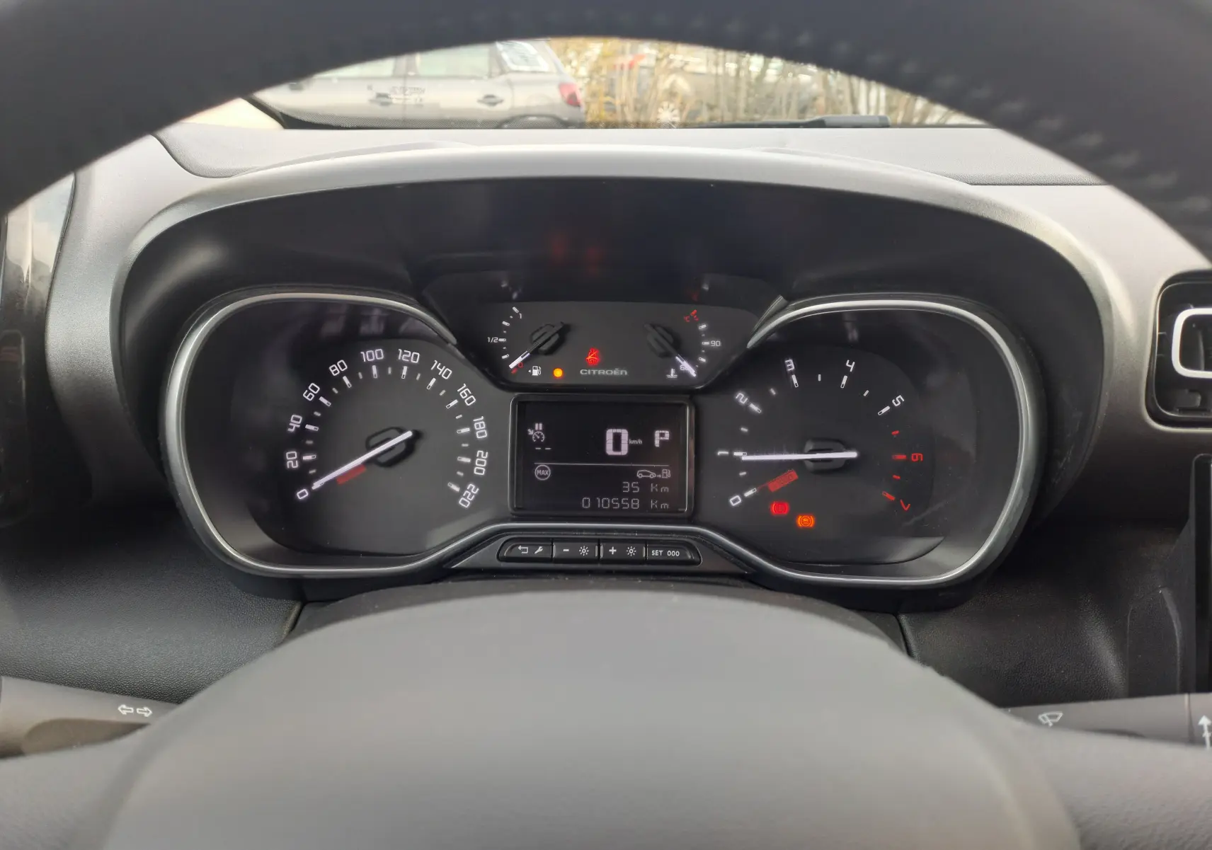 Vue rapprochée du tableau de bord de la Citroën C3 Aircross blanc banquise, affichant le compteur et les voyants allumés.