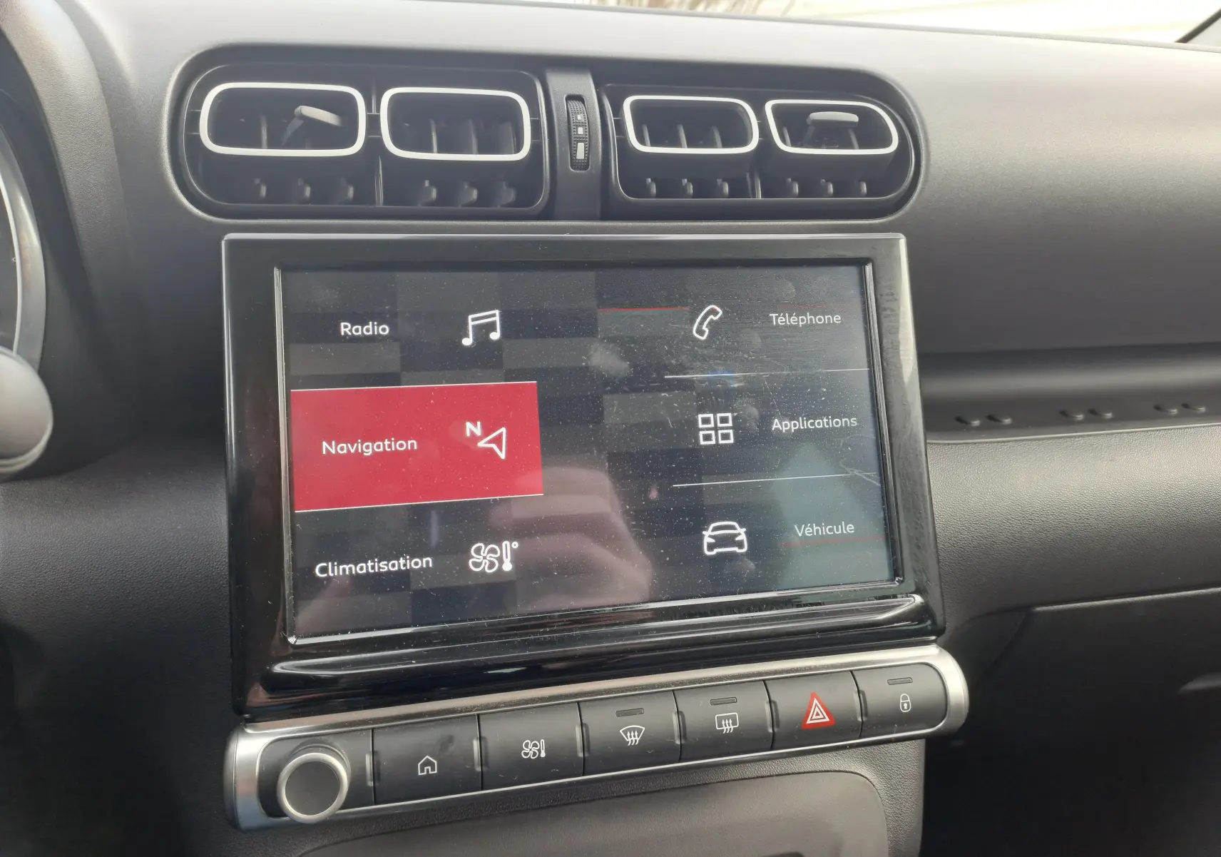 Vue rapprochée de l'écran tactile central et des aérateurs noirs à contours argentés dans l'habitacle du Citroën C3 Aircross blanc banquise 2024.