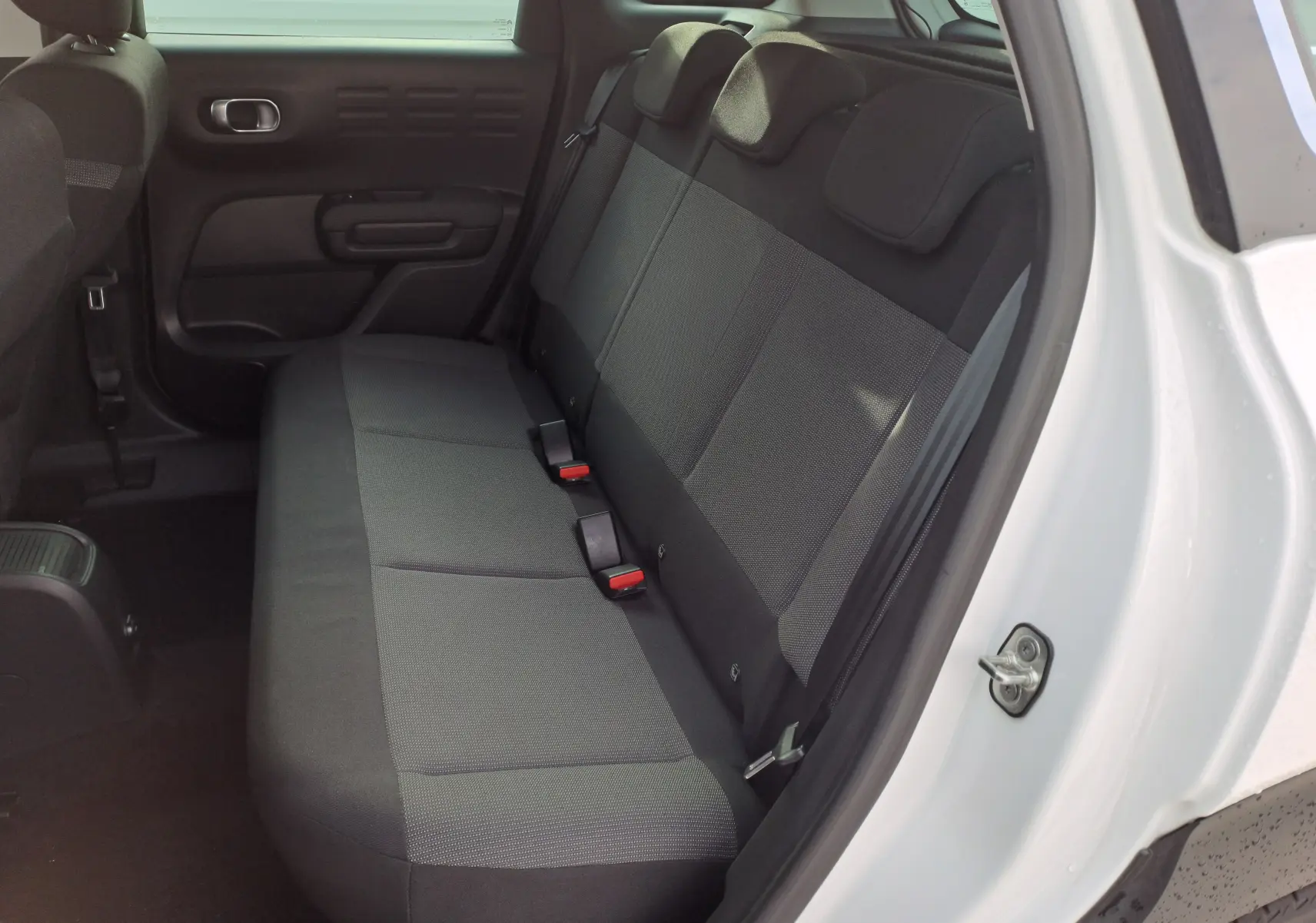 Vue côté gauche de la banquette arrière grise du Citroën C3 Aircross blanc banquise 2024 avec porte ouverte.