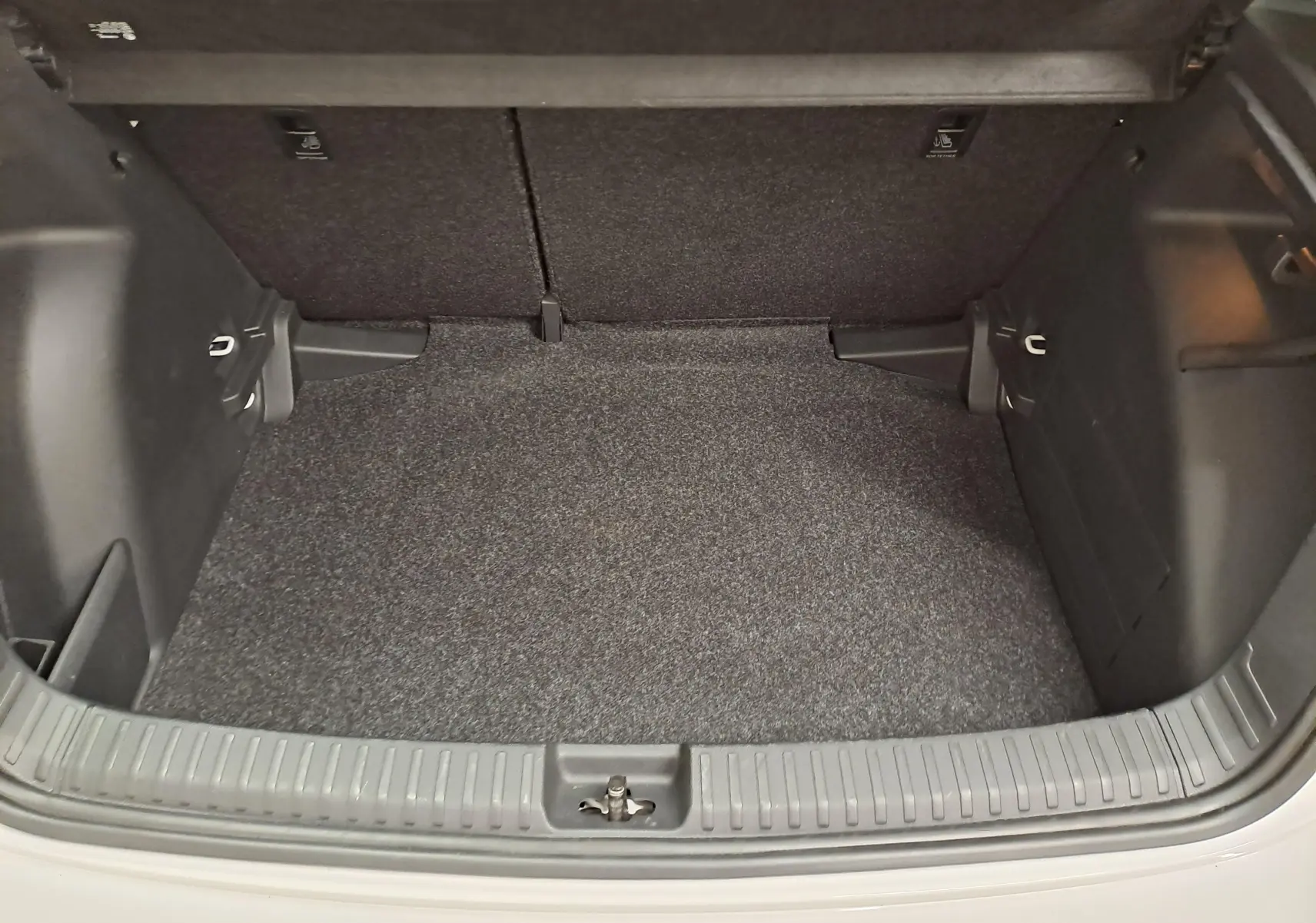 Coffre ouvert vu de l'arrière d'une Skoda Fabia 2023 blanc candy, montrant un espace de chargement propre et vide.