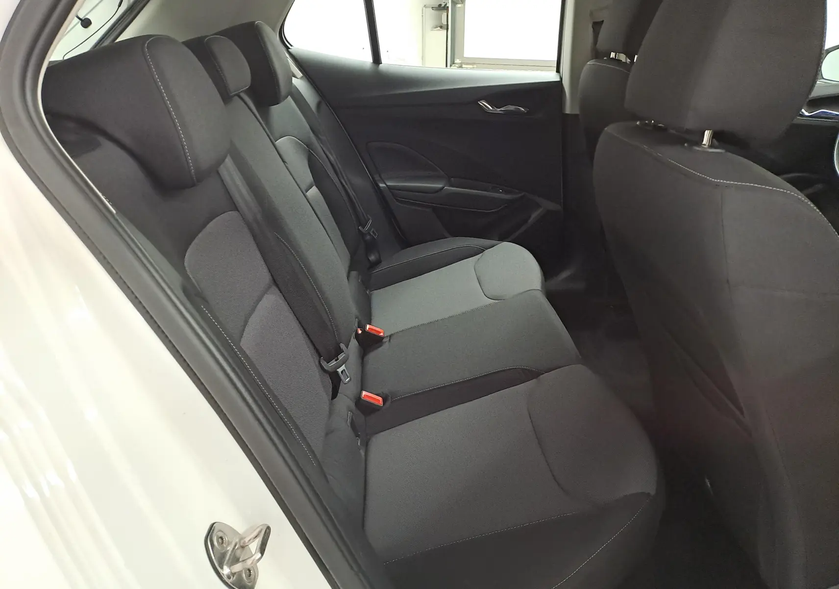 Intérieur arrière de la Skoda Fabia 2023 blanc candy, vue côté gauche sur les sièges tissu noirs avec appuie-têtes.