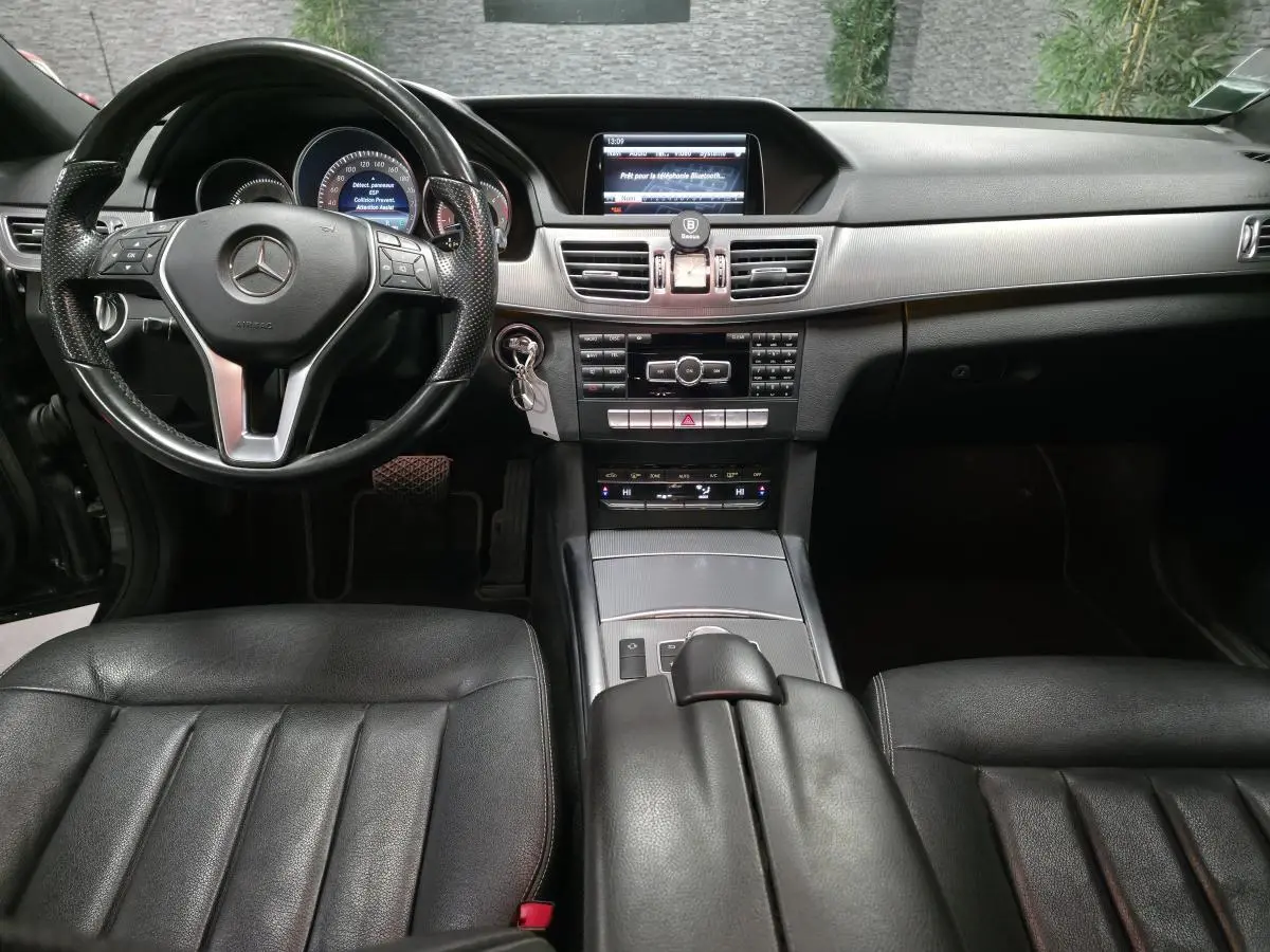 Intérieur noir de la Mercedes Classe E 300 BlueTEC Hybrid 2015, vue frontale sur tableau de bord et volant cuir.
