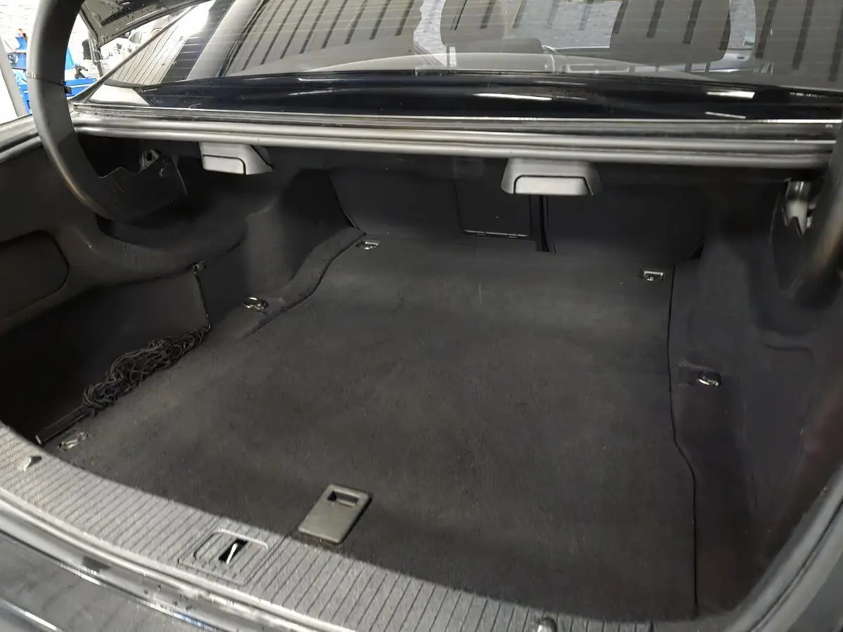 Coffre ouvert d'une Mercedes Classe E noire, vue intérieure montrant un espace de chargement propre et spacieux.