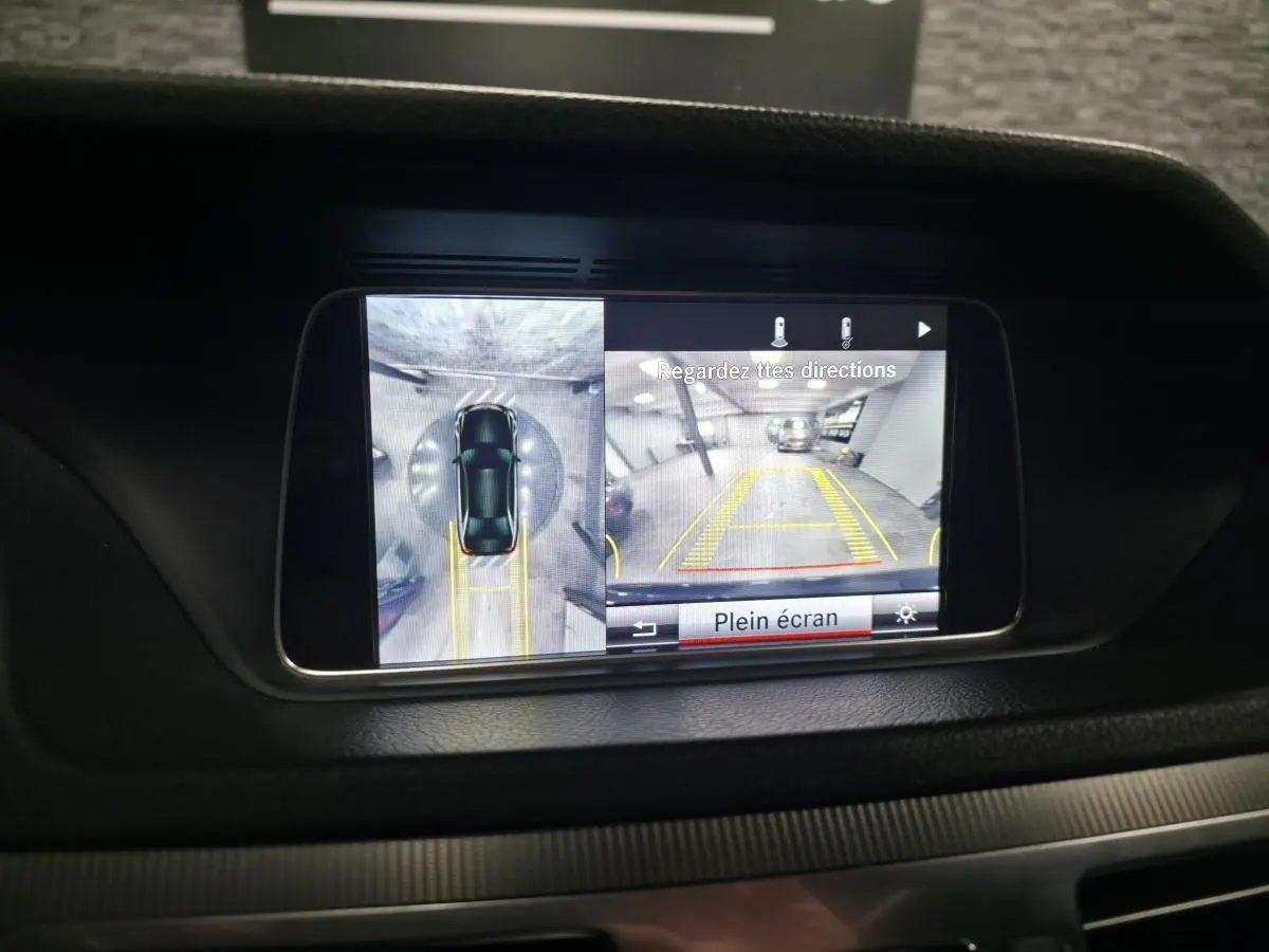 Écran multimédia montrant la caméra 360° et de recul de la Mercedes Classe E noire, vue intérieure du tableau de bord.