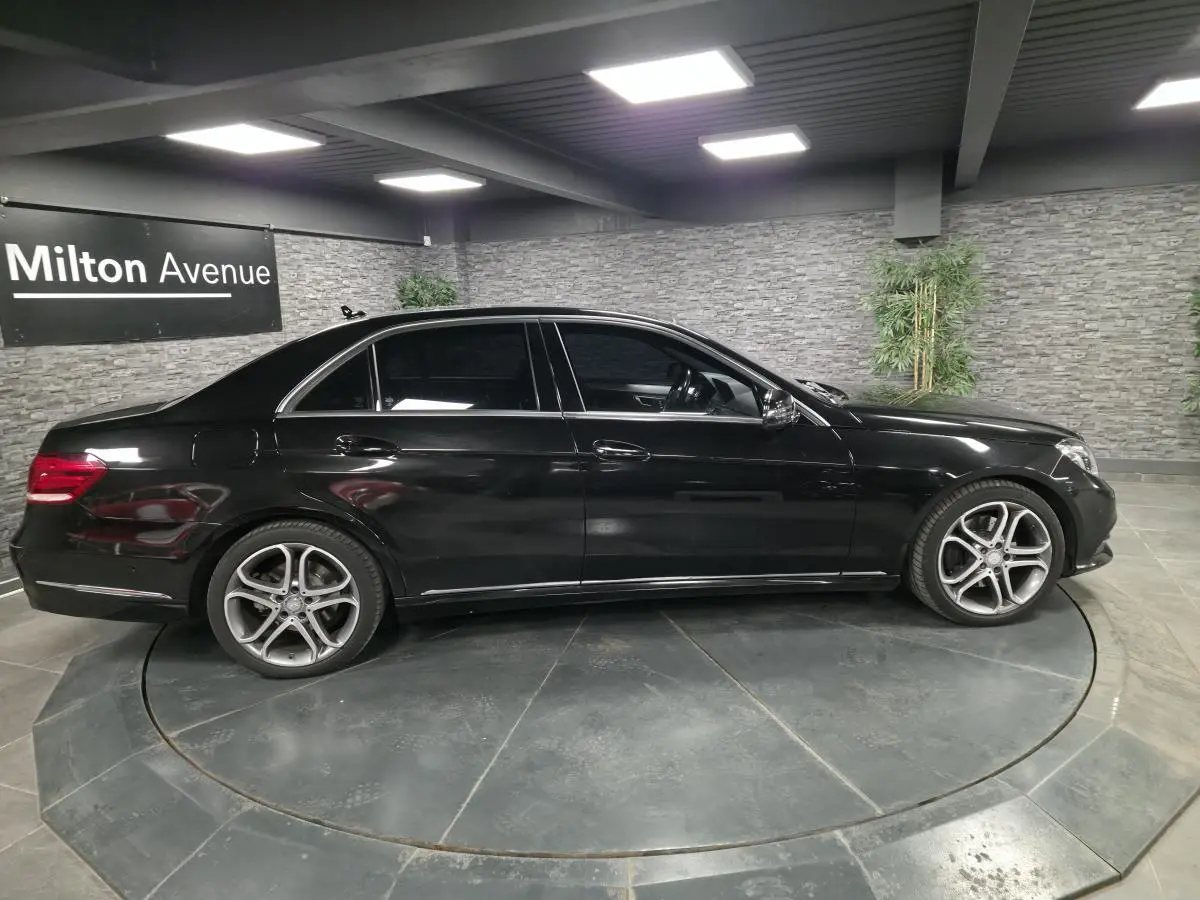 Profil droit d'une Mercedes Classe E noire de 2015 avec jantes alliage 18 pouces et vitres teintées dans un showroom.