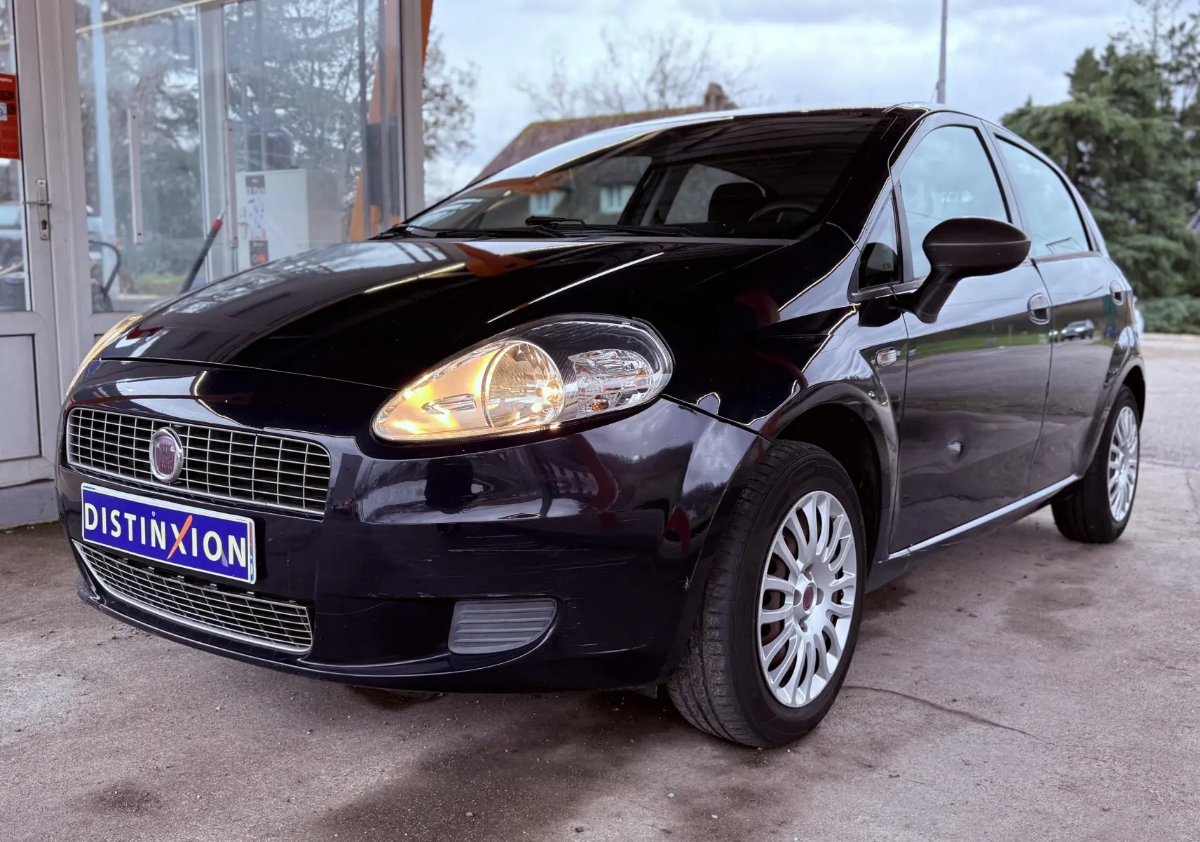 Fiat Punto noire vue en 3/4 avant droit avec phare avant allumé et jantes argentées.