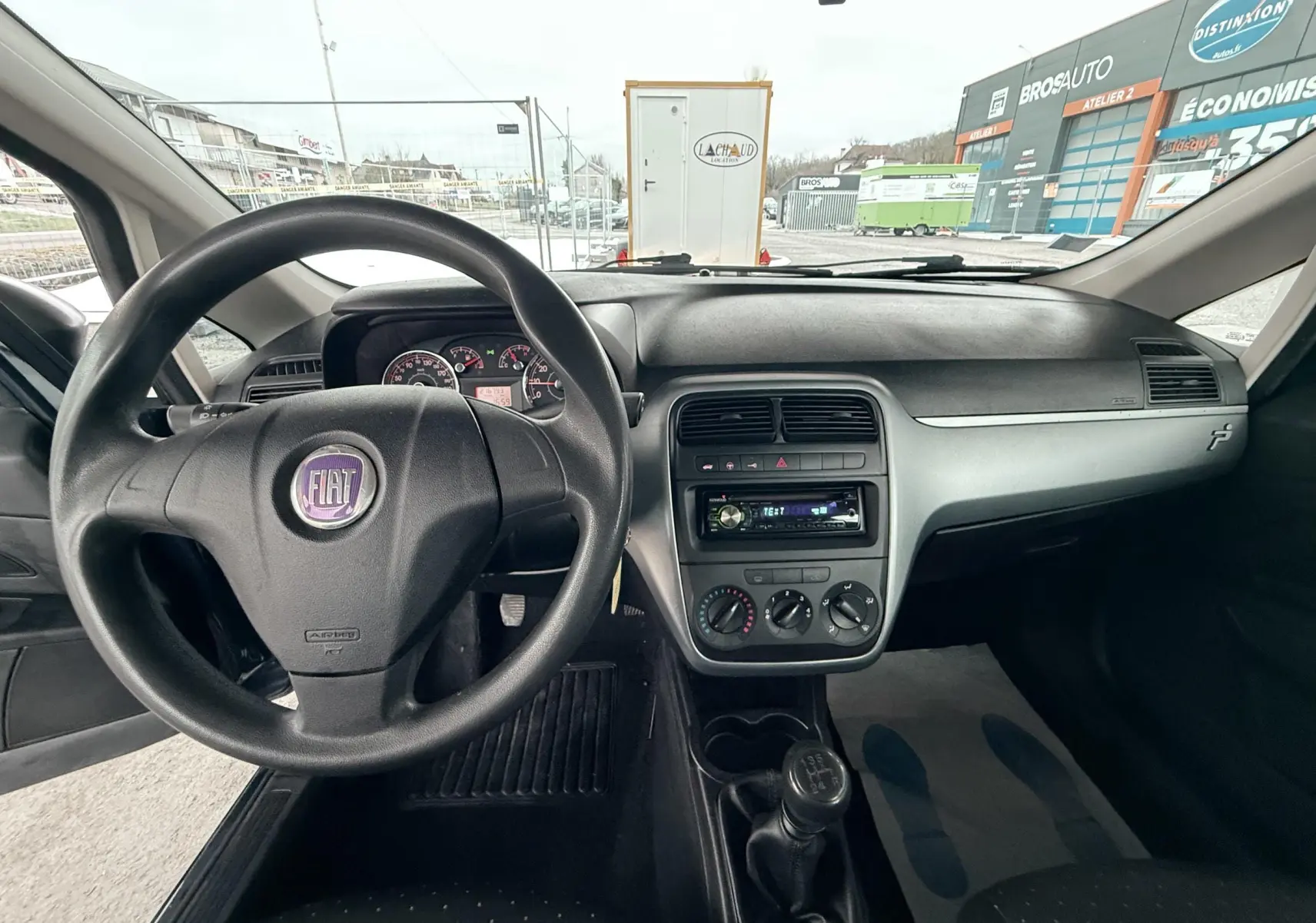 Vue intérieure du tableau de bord et volant noir d'une Fiat Punto 1.2 i 65 de 2009 avec boîte manuelle.