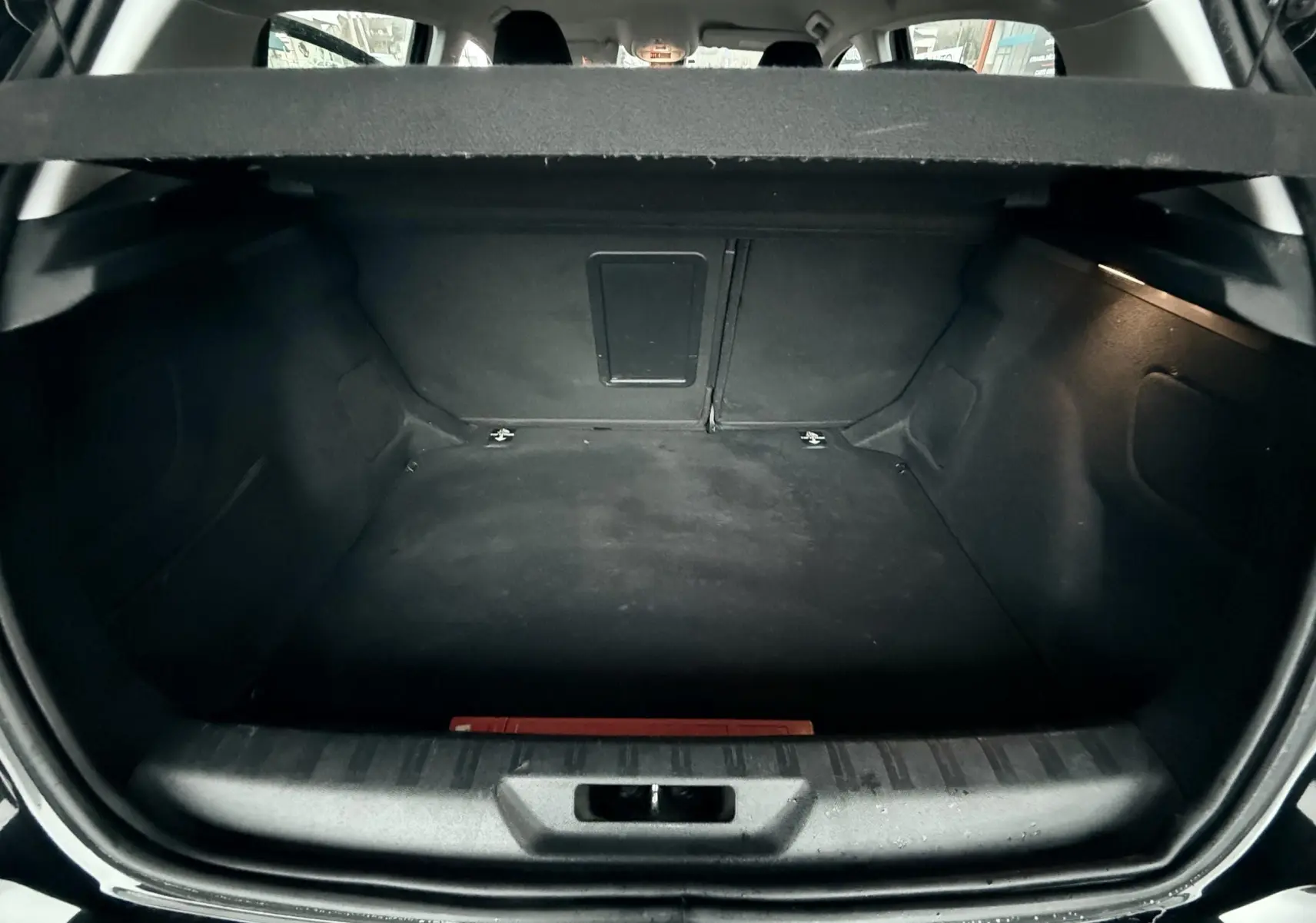 Vue intérieure du coffre noir d'une FIAT Punto 1.2 i 65 de 2009, montrant un espace de chargement vide et propre.