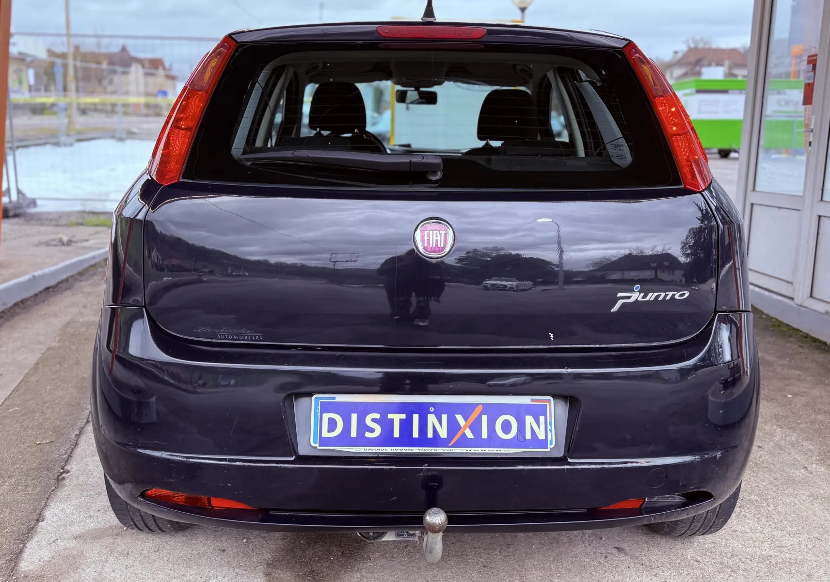 Vue arrière d’une FIAT Punto noire de 2009 avec attelage et plaque d’immatriculation Distinxion visible.
