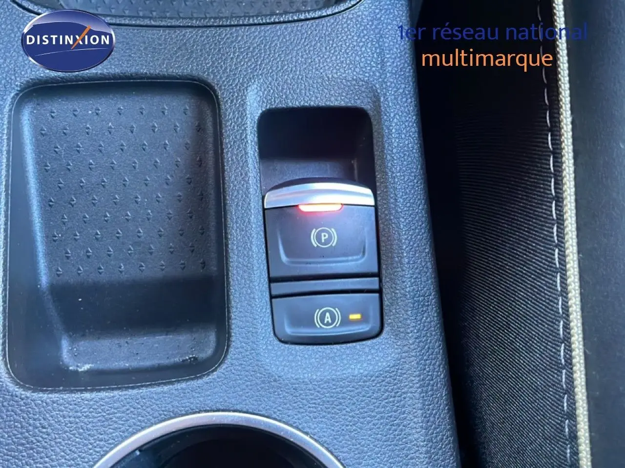 Gros plan sur la console centrale noire du Renault Symbioz 2025, avec boutons de frein à main et arrêt moteur éclairés.