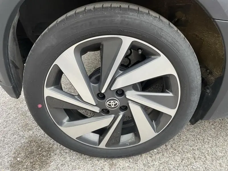 Gros plan sur la roue avant droite d'une Toyota Aygo X 2023, jante alliage bicolore avec logo Toyota au centre.
